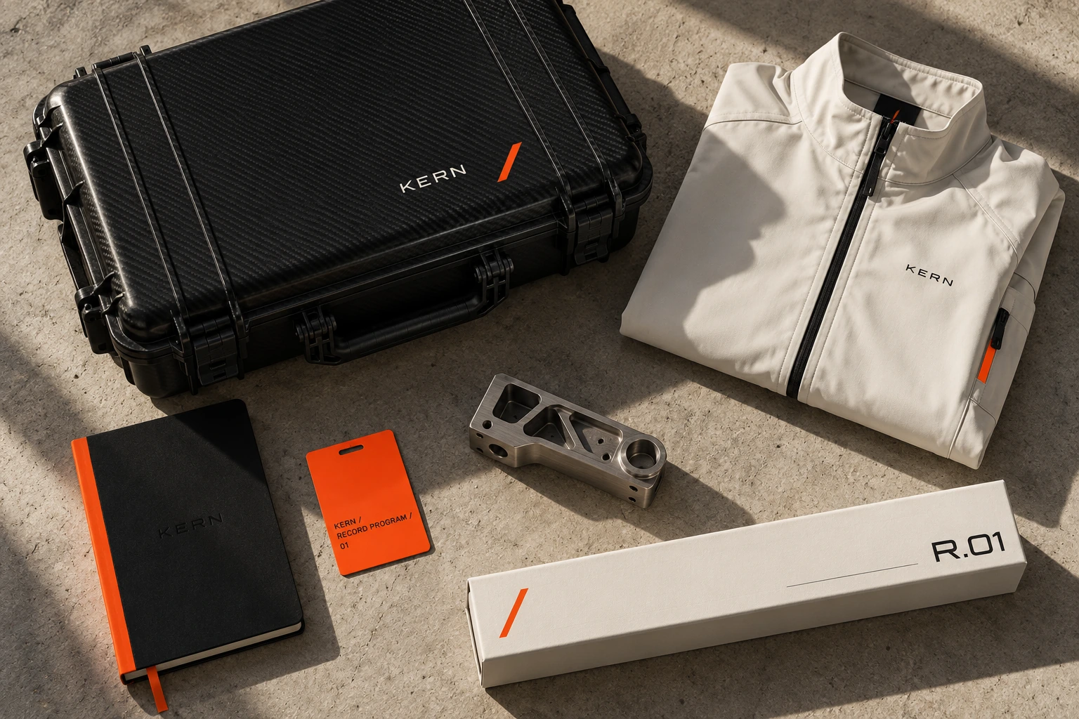 KERN identity applied to an ivory crew jacket, carbon equipment case, notebook, orange access card and component packaging