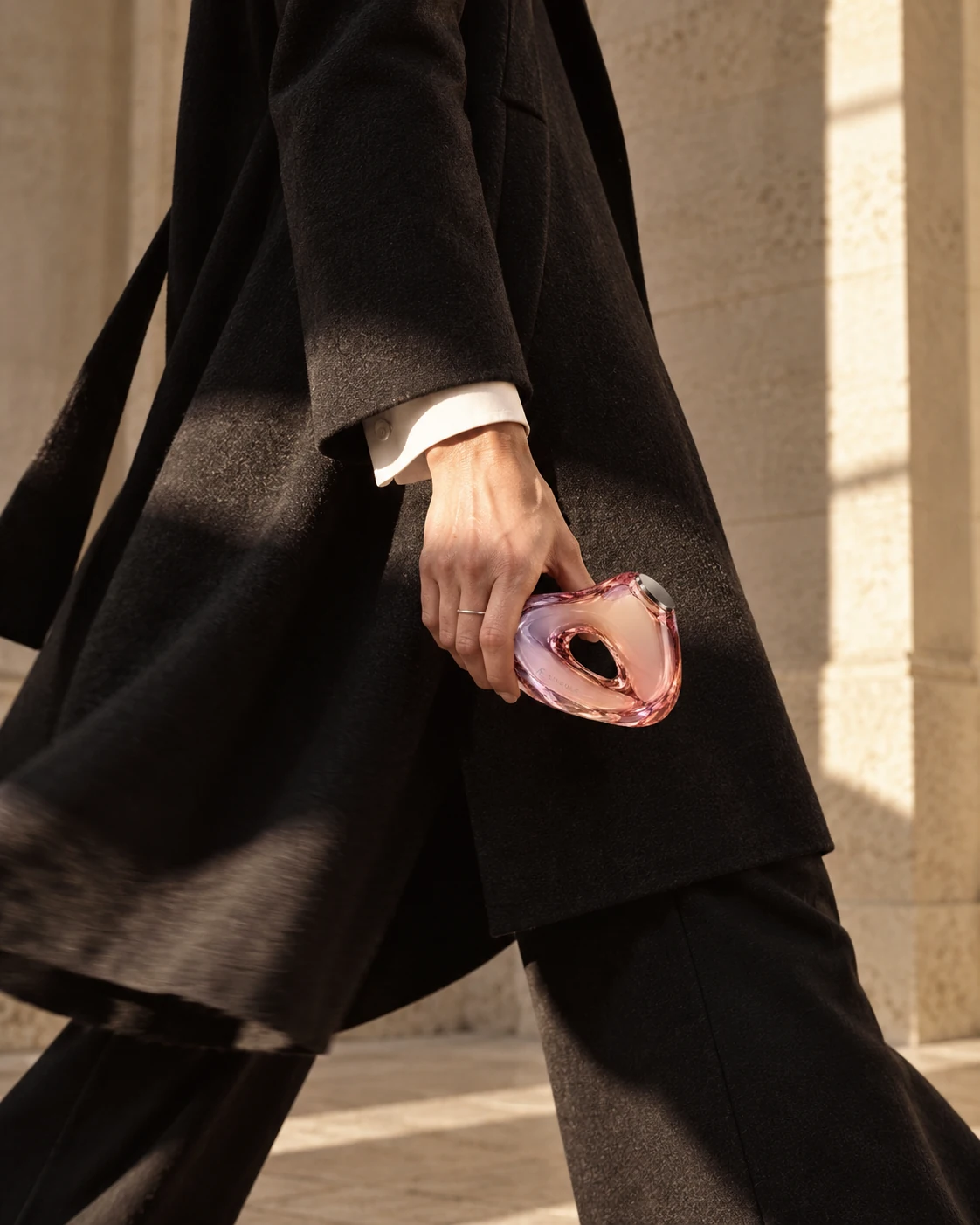 Fashion campaign composition: a woman in motion carrying the sculptural bottle